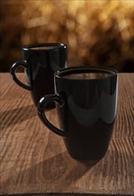 Black cups with coffee on an old wooden board