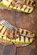 Grilled vegetables on rustic bread over wood table