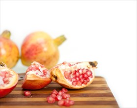 Fresh pomegranate fruit on wood over white background