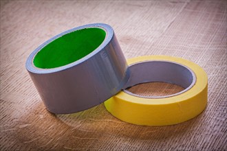 Yellow and blue rolls of adhesive tape on vintage brown wooden board construction concept