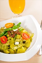 Fresh lumaconi pasta and pesto sauce with vegetables and sundried tomatoes