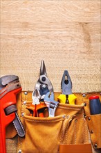 Construction tools in tool belt Monkey spanner Pliers Pliers on wooden board