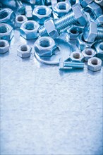 Pile of stainless steel threaded screws nuts and bolts washers on metallic background Construction concept