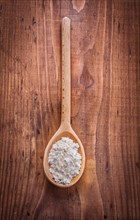Flour in a wooden spoon on an old wooden board