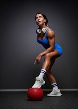 Sexy fitness woman. A beautiful athletic girl in a blue tracksuit posing in the studio. Red fitball