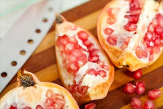 Fresh pomegranate fruit over wood cutting board with knife