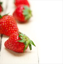 Fresh organic strawberry over white rustic wood table