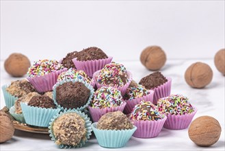 Dark rum balls with various sprinkles in pink and turquoise paper moulds