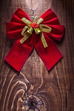 Beautiful red Christmas bow with gold ribbon and bells on an old wooden board