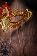 Close-up of a gold-coloured carnival mask on an old wooden board