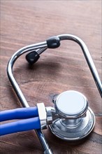 Close-up of a medical stethoscope on a vintage wooden board