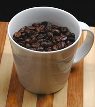Coffee beans on a cup on a wood board