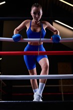 Woman boxer in blue gloves in the ring. Sports concept