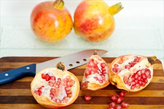 Fresh pomegranate fruit over wood cutting board with knife