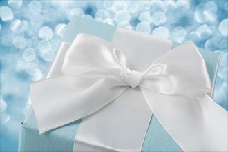 Top view of blue gift box with white ribbon on blurred background