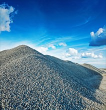 Big pile of grey granite gravel with sky background construction concept