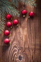 Small red Christmas baubles with fir tree branches on an old wooden board with copy space