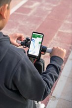 Person using a navigation app on a smartphone mounted on bicycle handlebars