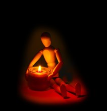 Wood mannequin and candle glowing on the dark over black background