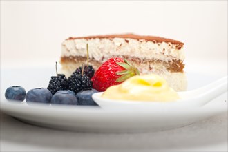 Classic Italian tiramisu dessert with berries and custartd pastry cream on side