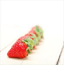 Fresh organic strawberry over white rustic wood table