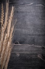 Golden wheat and rye ears on wooden board vertical view