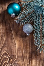 Blue and silver christmas balls and pinetree branch on old wooden board with copyspace