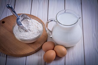Aerial view Egg Milk in jug Flour Bowl Shovel on white painted wooden board Food and drink Still life