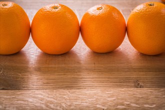 Four orange fruits organised in row on wooden board