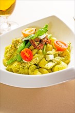 Fresh lumaconi pasta and pesto sauce with vegetables and sundried tomatoes