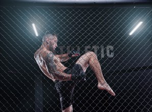 Powerful MMA fighter trains a knee strike in the octagon. The concept of sports