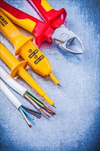 Yellow electrical tester wires cutting pliers on metallic background electricity concept