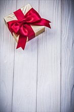 Gift box in glittery paper with bow on wooden board holidays concept