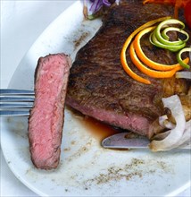 Fresh juicy beef ribeye steak grilled with orange and lemon peel on top and vegetable beside