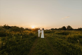 Loving couple of newlyweds at sunset in the field