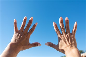 Woman's hands showing all ten fingers on a blue sky background