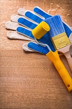Safety gloves with paint roller and brush on wooden board Construction concept