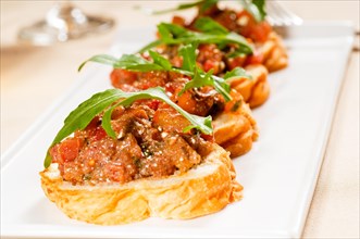 Fresh tipycal italian bruschetta with tomato and arugula on top