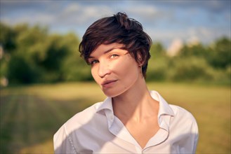 Retro portrait of a stylish beautiful woman in a white shirt on the background of a sunny meadow. The concept of style and fashion