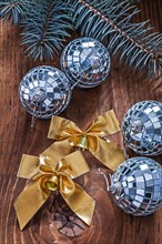 Golden bows and Christmas disco baubles with Christmas tree branch on an old wooden board