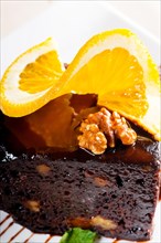 Fresh baked delicious chocolate and walnuts cake with slice of orance on top