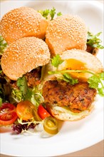 Four fresh and delicious mini chicken burgers on a plate