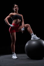 Athletic girl working out in gym. Fitness woman training with pilates ball. Mixed media