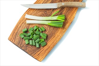 Green spring chopped scallion on wooden board and kitchen knife isolated white