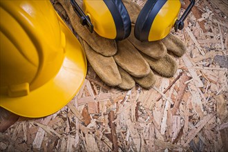 Protective leather gloves hard hat ear protectors on OSB