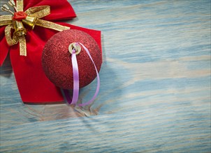 Red Christmas ball bow with bell on wooden board holidays concept