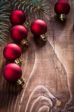 Group of red Christmas baubles and fir branch on an old wooden board