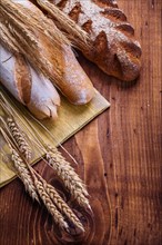 Composition of bread and ears of wheat on old wooden boards