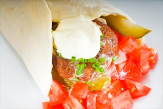 Fresh traditional falafel wrap on pita bread with fresh chopped tomatoes