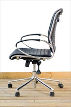 Modern black leather office chair on wood floor over white background
